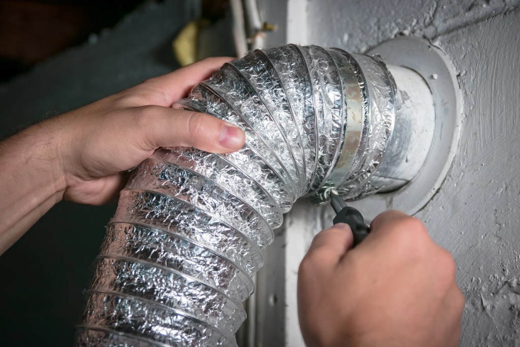 HVAC team member unscrewing dryer ventilation duct for cleaning