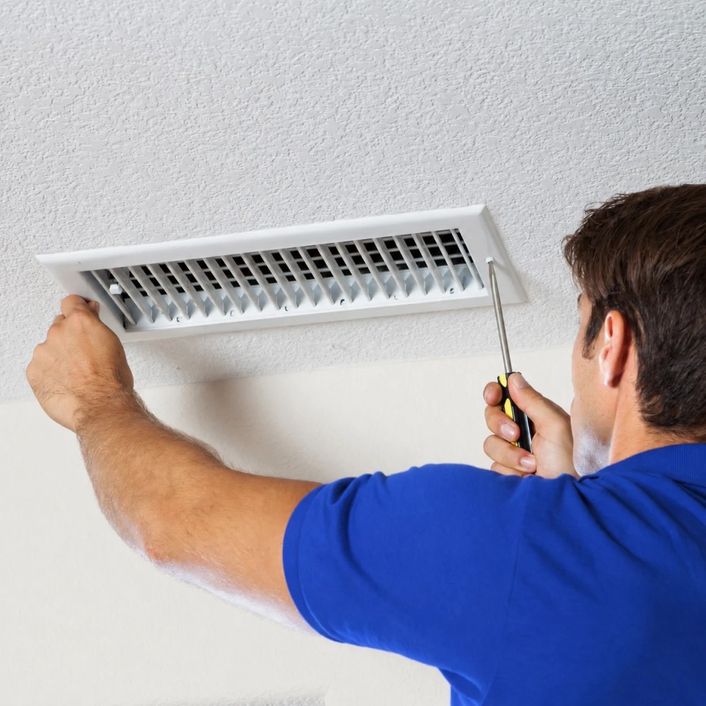 HVAC team member unscrewing air vent cover for cleaning