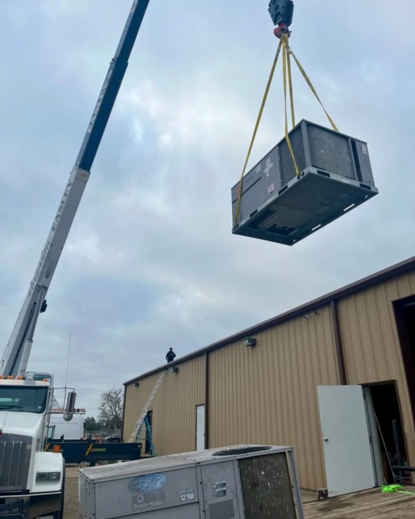 crane holding commercial hvac unit to lift to top of commercial building