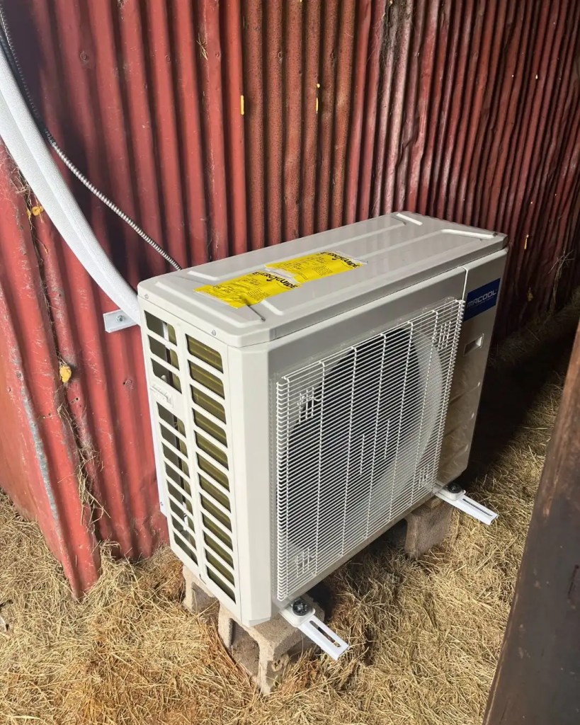 mini split outdoor condenser unit on red barn